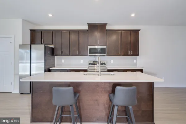 a kitchen with stainless steel appliances a table chairs refrigerator and wooden cabinets