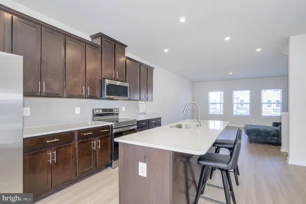 a kitchen with stainless steel appliances kitchen island granite countertop a refrigerator a stove a sink a dining table and chairs