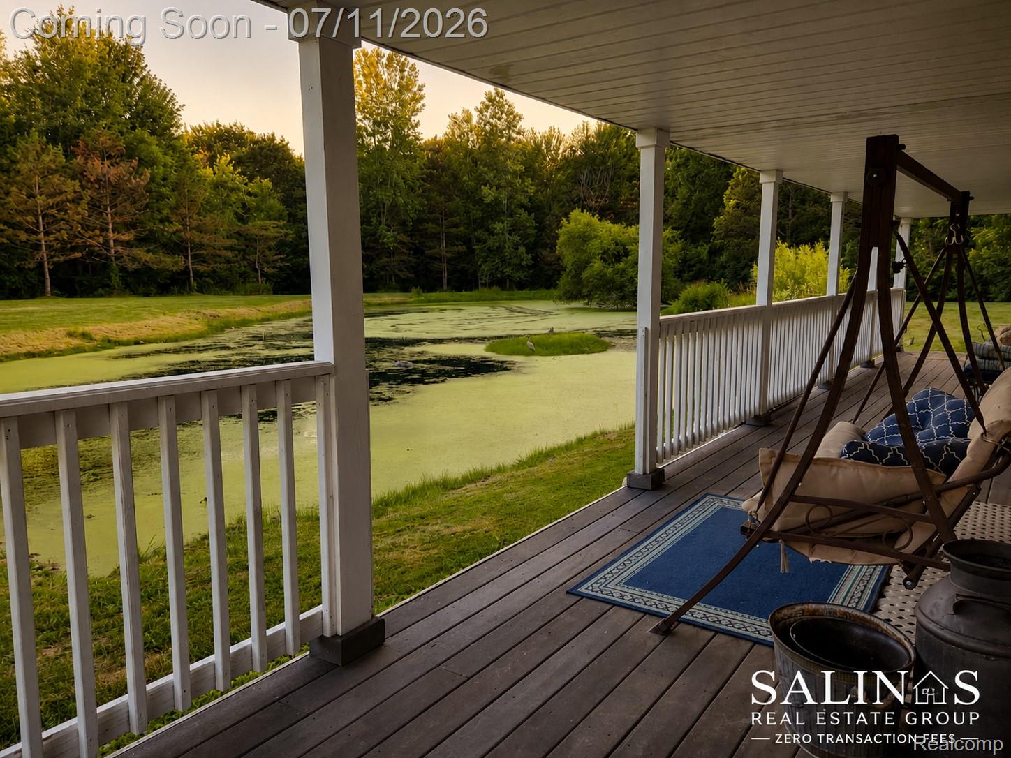 2120 Montague Road Davison, MI 48423 - Photo 20 of 37 Expansive covered porch featuring a wood-finish floor, white railing, and columns overlooking a natural pond