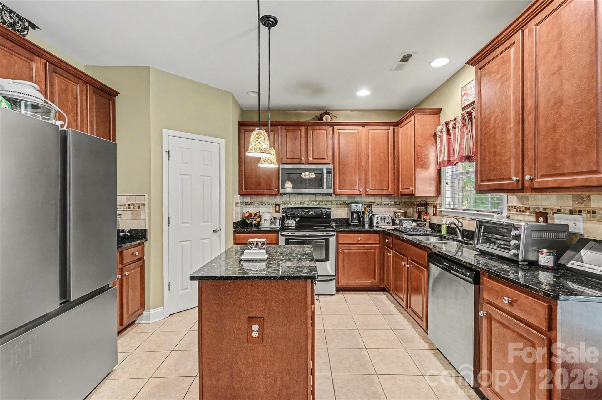 10812 Clark Street Davidson, NC 28036 - Photo 11 of 32 a kitchen with stainless steel appliances granite countertop a refrigerator a sink a stove a microwave and island
