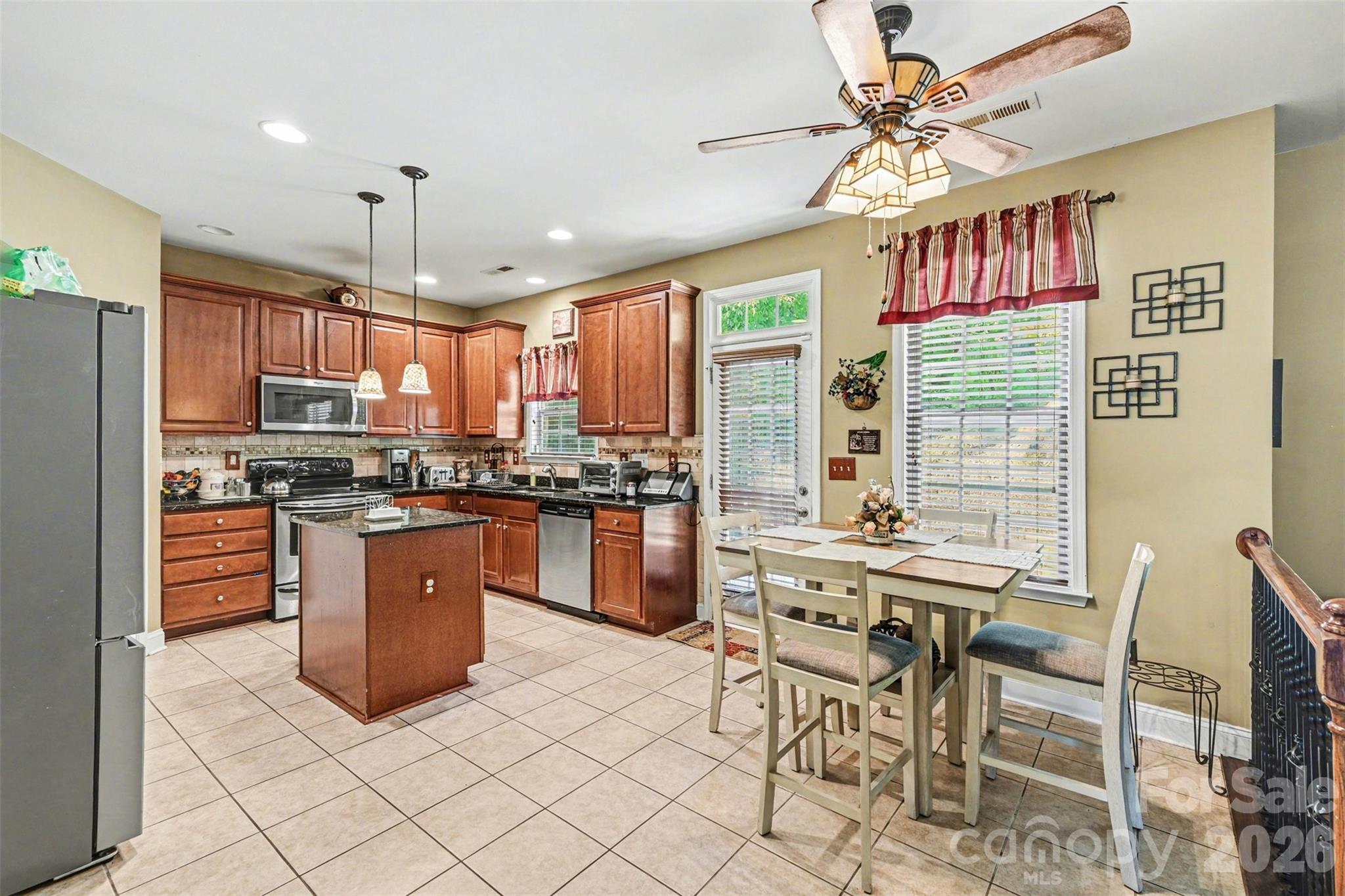 10812 Clark Street Davidson, NC 28036 - Photo 13 of 32 a kitchen with stainless steel appliances granite countertop a stove a refrigerator a sink a dining table and chairs with wooden floor