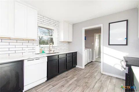 a kitchen with a sink cabinets and wooden floor