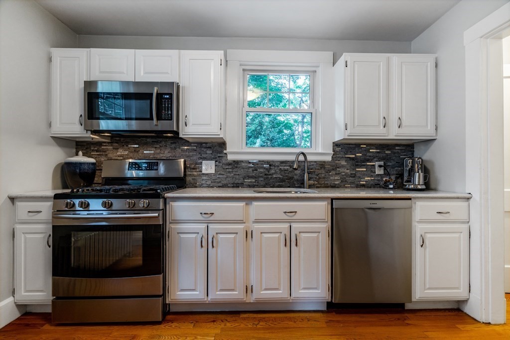 175 Florence Road Waltham, MA 02453 - Photo 10 of 24 a kitchen with granite countertop a stove a microwave a sink and cabinets