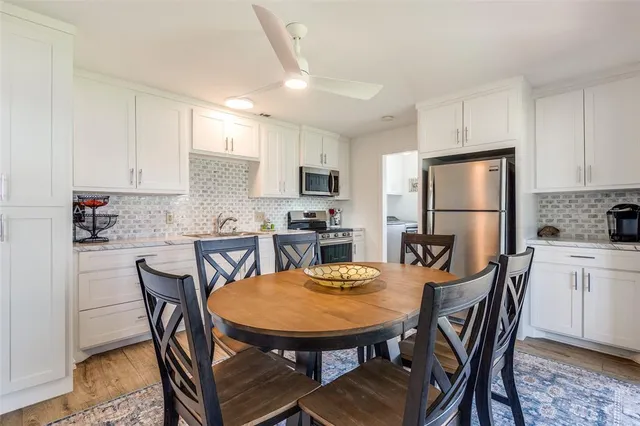 a kitchen with stainless steel appliances granite countertop a dining table chairs refrigerator and microwave
