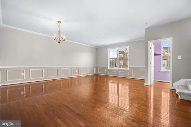 a view of an empty room with window and wooden floor