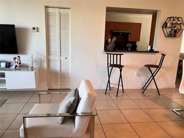 a living room with chairs and kitchen view