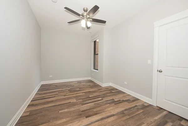 a view of a room with wooden floor and a ceiling fan