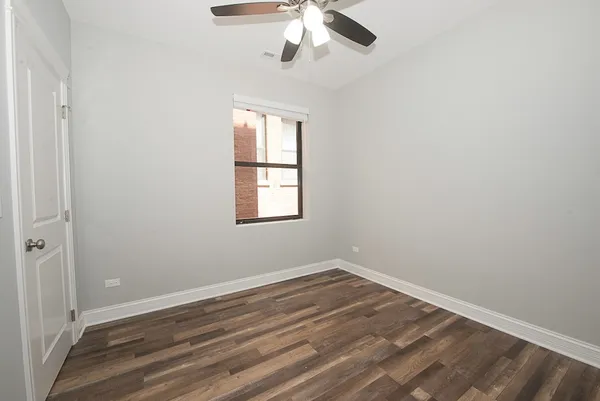 an empty room with wooden floor fan and windows