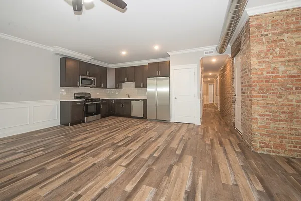 a large kitchen with a wooden floor and stainless steel appliances