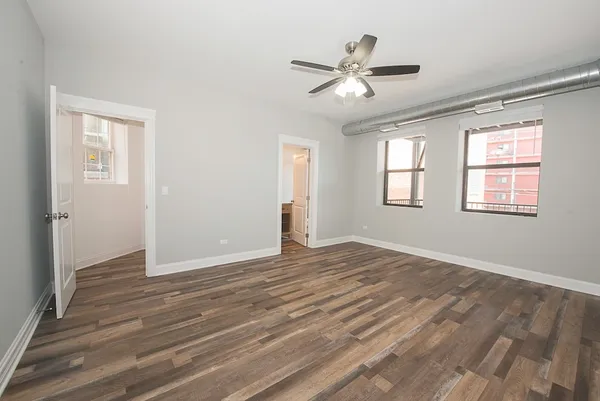 a view of empty room with wooden floor and fan