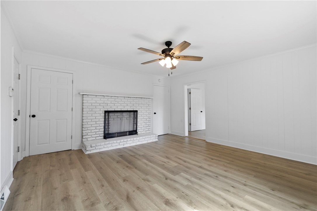 201 South 8th Street Easley, SC 29640 - Photo 5 of 28 Warm wood-toned floors and a classic brick fireplace anchor this welcoming living area.