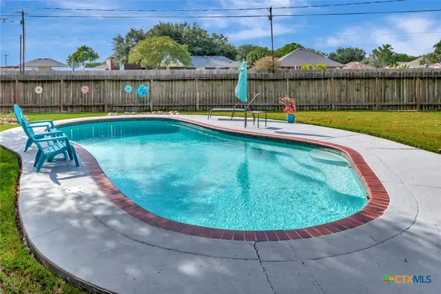 a view of a swimming pool with a yard and sitting area