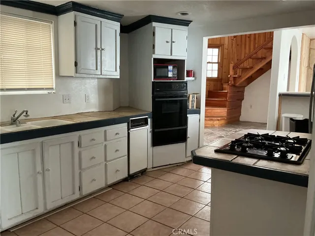 a kitchen with granite countertop a sink stove and cabinets