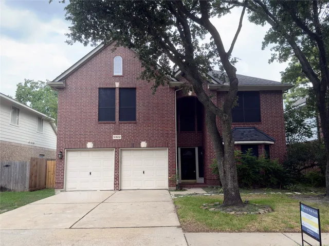 a front view of a house with a yard and tree
