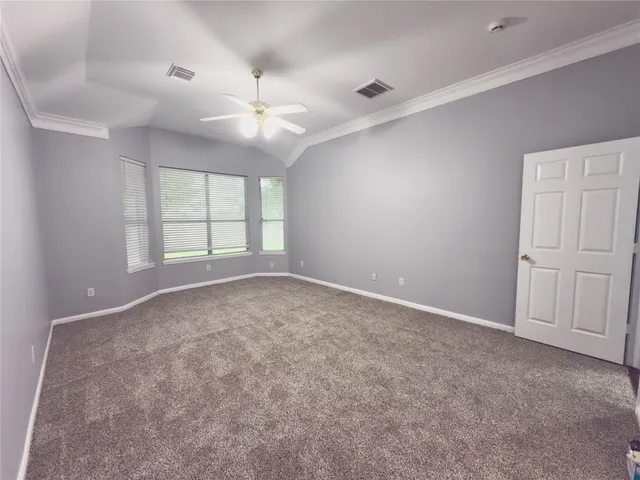 an empty room with windows and chandelier fan