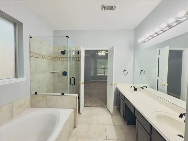 a spacious bathroom with a tub sink shower and mirror