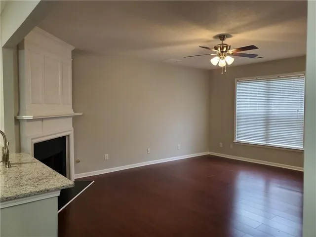 a view of a livingroom with a fireplace a ceiling fan and wooden floor
