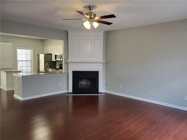 a view of a kitchen with a fireplace a ceiling fan and wooden floor