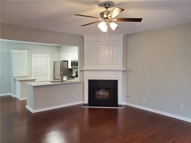 a view of an empty room with wooden floor and a fireplace