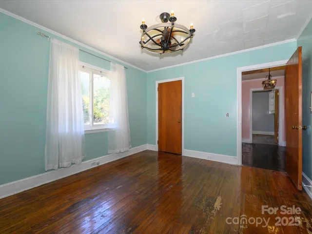 an empty room with wooden floor closet and windows