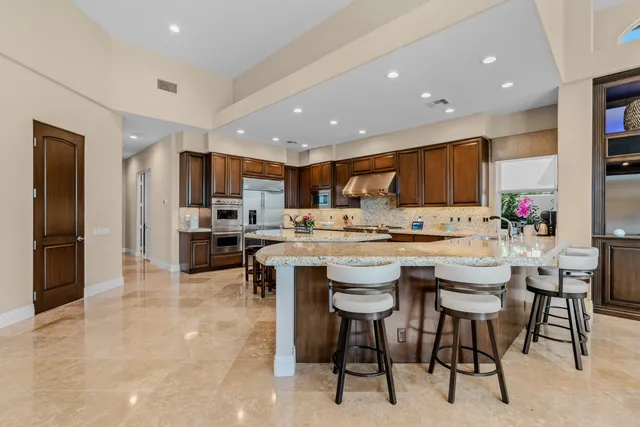 a kitchen with stainless steel appliances granite countertop a white cabinets and chairs