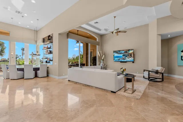 a living room with furniture kitchen view and a large window