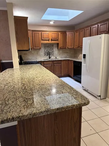 a kitchen with kitchen island granite countertop a sink stove and refrigerator