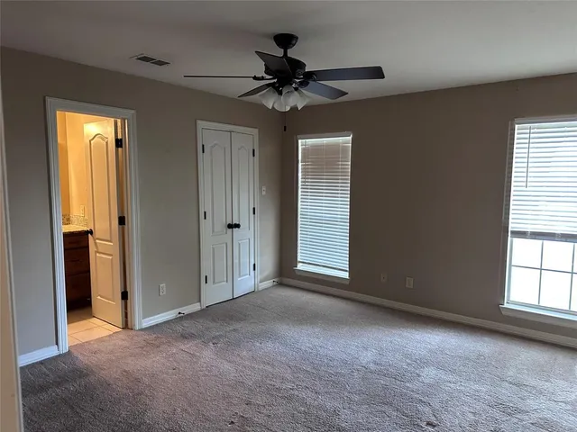an empty room with closet and a ceiling fan