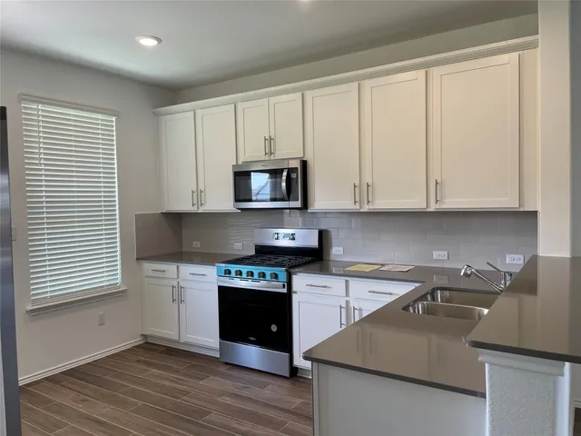 a kitchen with stainless steel appliances granite countertop a stove a sink and a microwave