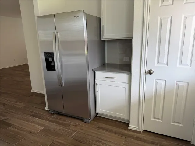 a view of a refrigerator in kitchen with stainless steel appliances wooden floor