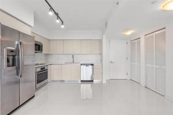 a kitchen with stainless steel appliances granite countertop a refrigerator a stove and a sink