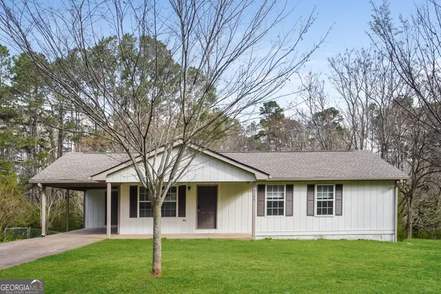 a view of a yard in front of a house with plants and large tree