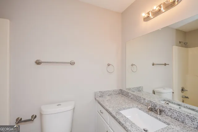 a bathroom with a granite countertop sink a toilet and a mirror