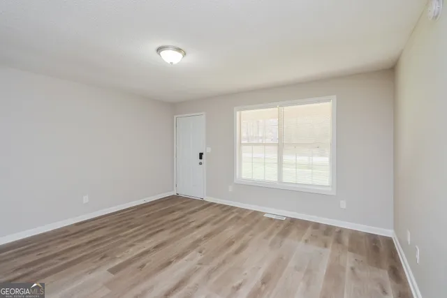 an empty room with wooden floor and windows