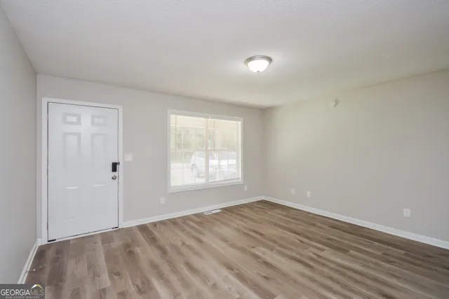 a view of an empty room with wooden floor and a window