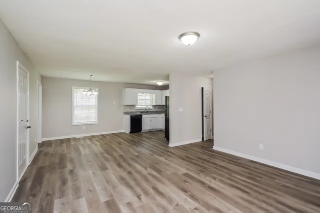 a view of an empty room with window and wooden floor