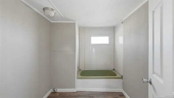 a view of an empty room with wooden floor and a ceiling fan