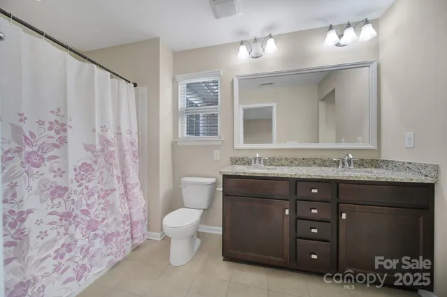a bathroom with a granite countertop toilet sink and mirror
