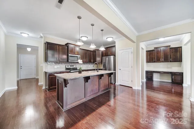 a kitchen with stainless steel appliances kitchen island granite countertop a stove a sink and a refrigerator