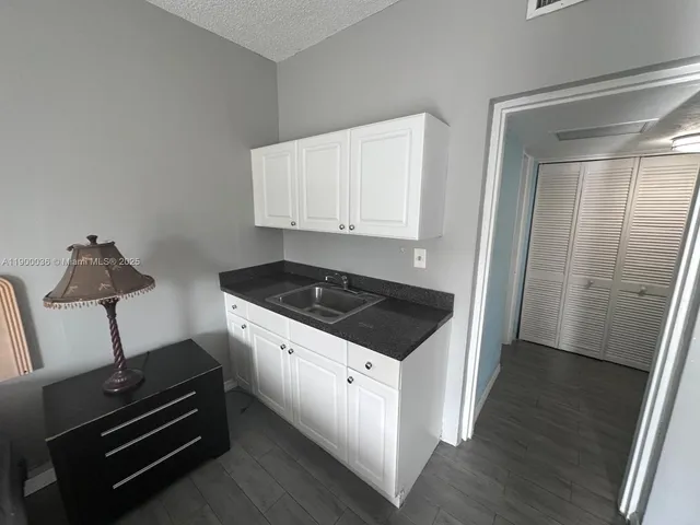 a view of a refrigerator in kitchen and an empty room