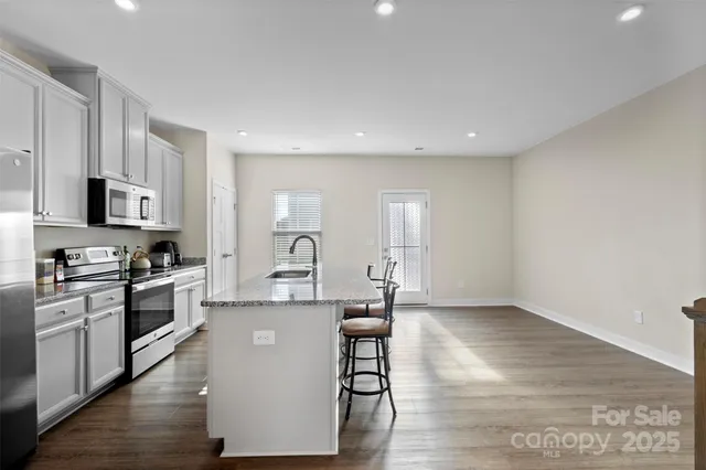 a large kitchen with cabinets wooden floor and stainless steel appliances