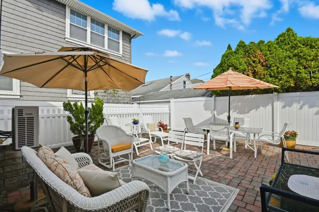 a view of a patio with chairs and table under an umbrella with a barbeque
