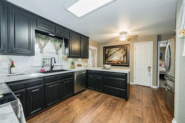 a kitchen with stainless steel appliances granite countertop cabinets a sink dishwasher a stove and a refrigerator with wooden floor