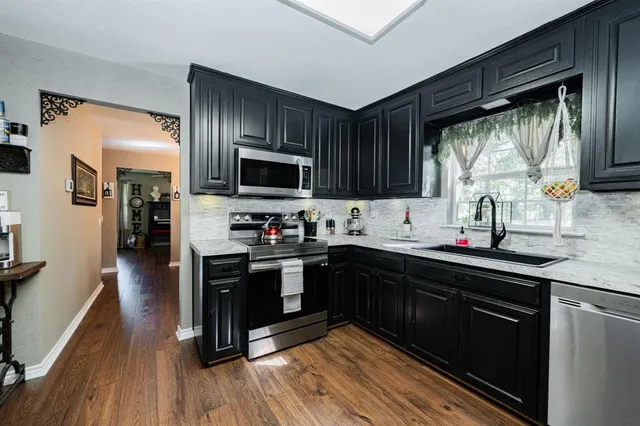 a kitchen with stainless steel appliances granite countertop a stove a sink dishwasher a refrigerator and a microwave oven with wooden floor