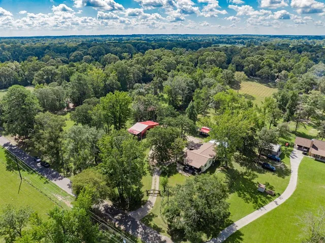 an aerial view of residential house with outdoor space and trees all around