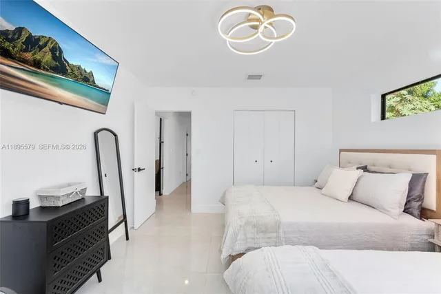 a bedroom with a bed and a flat tv screen on the dresser