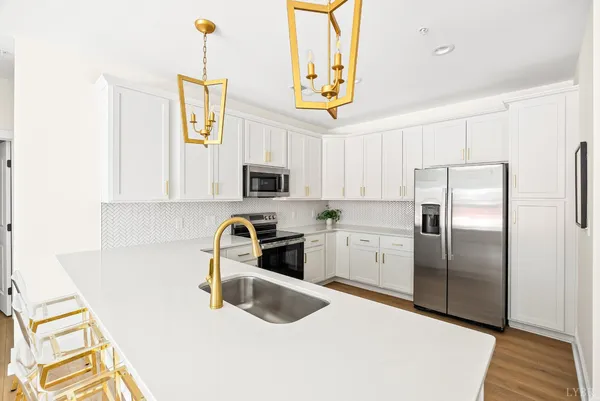 a kitchen with stainless steel appliances granite countertop a sink a stove a refrigerator a washer dryer and white cabinets