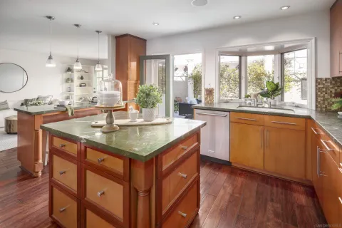 a dining hall with stainless steel appliances granite countertop a sink a stove and wooden floors