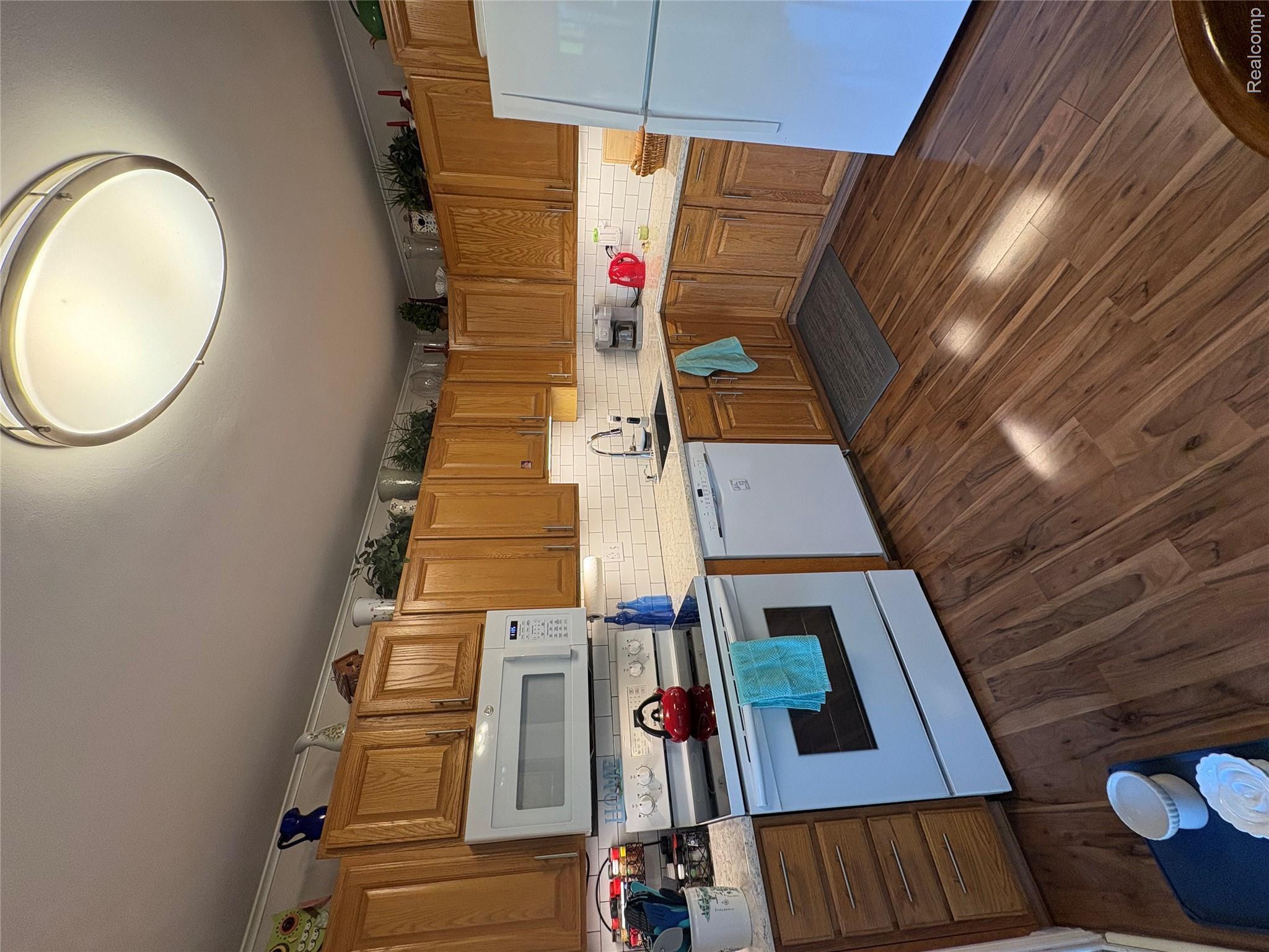 1030 Larson Court Rochester, MI 48307 - Photo 3 of 21 Kitchen featuring white appliances, wood finish cabinetry, dark wood-style floors, ornamental molding, and tasteful backsplash