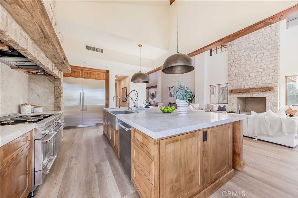 35995 Summit Circle Temecula, CA 92592 - Photo 29 of 75 a kitchen with stainless steel appliances granite countertop a stove and a fireplace with wooden floor